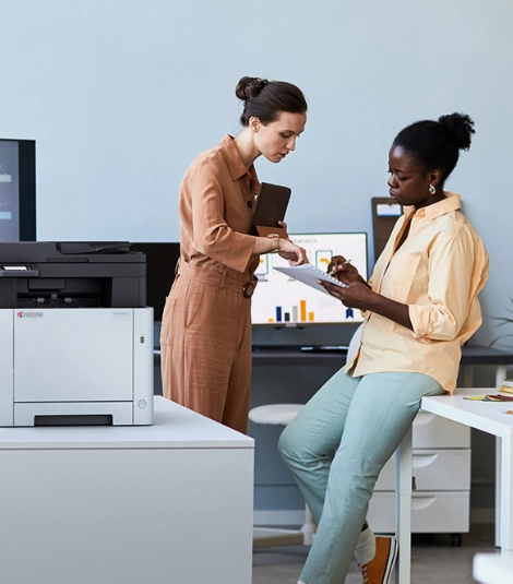 Women collaborating in office setting with printer